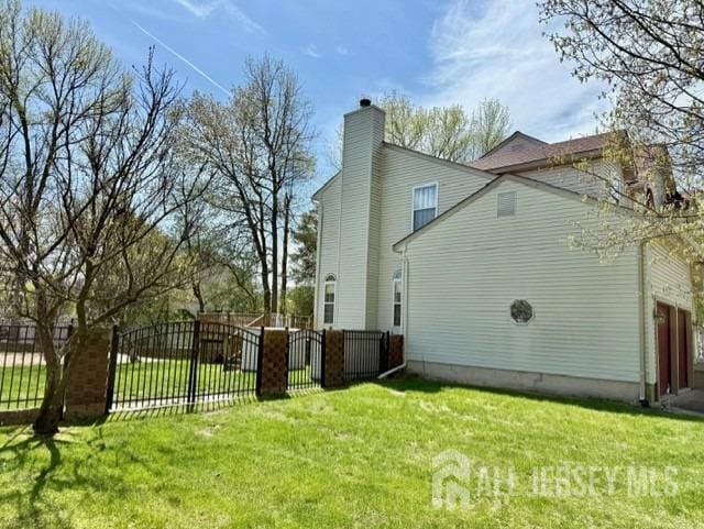 view of home's exterior with fence private yard, a lawn, and a chimney