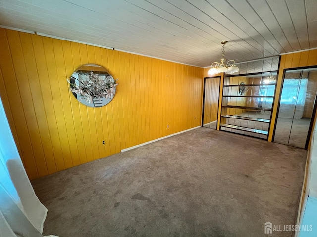 carpeted spare room with wooden walls and a chandelier