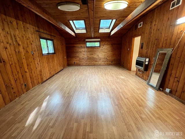 spare room featuring light hardwood / wood-style flooring, wooden walls, lofted ceiling with skylight, heating unit, and wooden ceiling