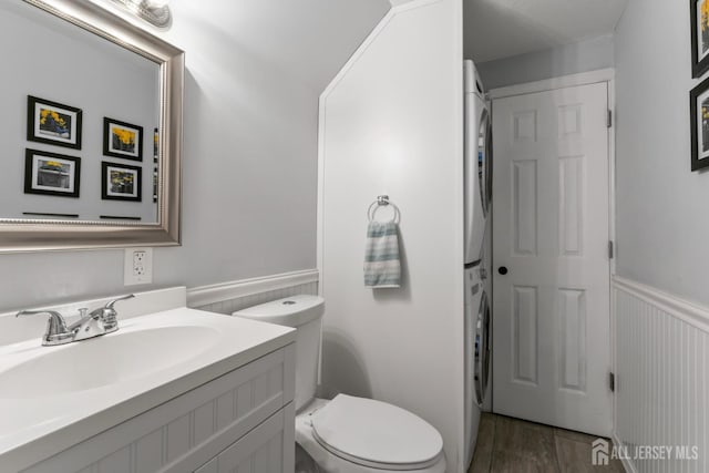 21 Haug St, Union Beach, NJ 07735 - half bathroom featuring stacked washer / dryer, a wainscoted wall, vanity, toilet, and wood finished floors