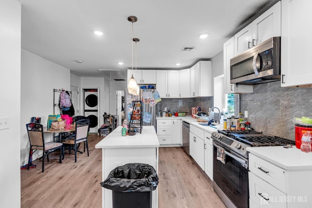 176 Main St, East Brunswick, NJ 08816 - kitchen with appliances with stainless steel finishes, estacked washer and dryer, a center island, light wood-type flooring, and white cabinetry