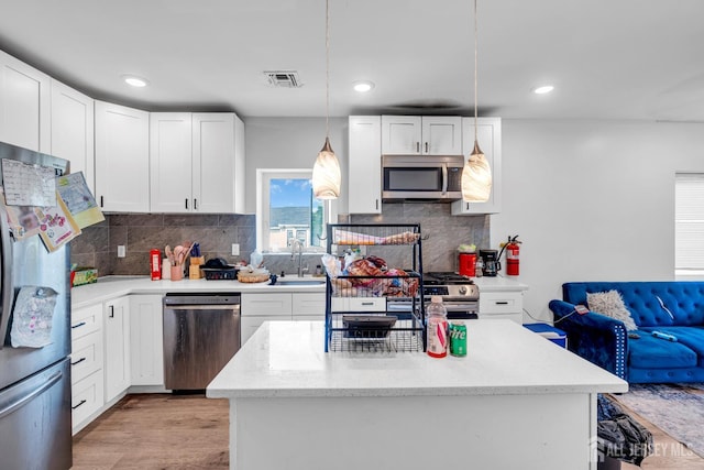 176 Main St, East Brunswick, NJ 08816 - kitchen with stainless steel appliances, white cabinetry, light wood finished floors, tasteful backsplash, and pendant lighting