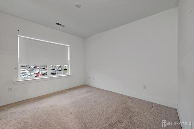 unfurnished room featuring carpet, visible vents, and baseboards