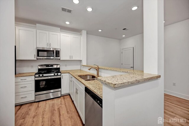 kitchen featuring white cabinetry, light stone countertops, kitchen peninsula, and stainless steel appliances