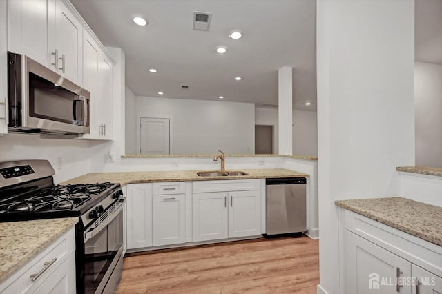 kitchen with visible vents, white cabinets, appliances with stainless steel finishes, light wood-type flooring, and a sink