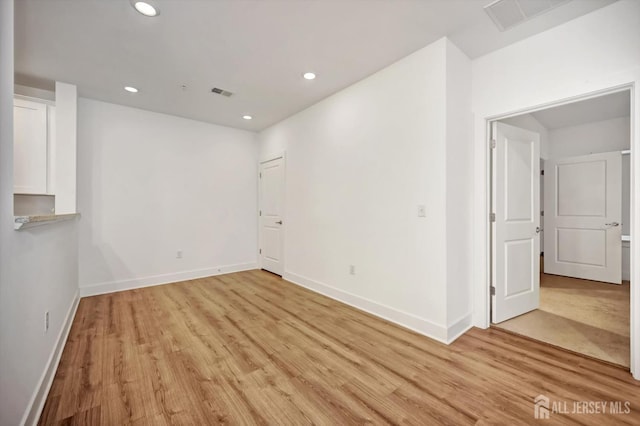 unfurnished room featuring baseboards, light wood-style flooring, visible vents, and recessed lighting