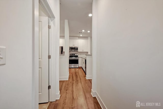 hall with recessed lighting, light wood-style flooring, and baseboards