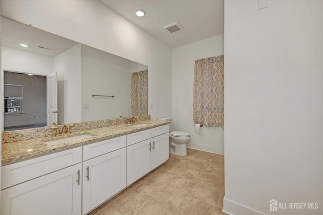 full bath with visible vents, double vanity, a sink, and toilet