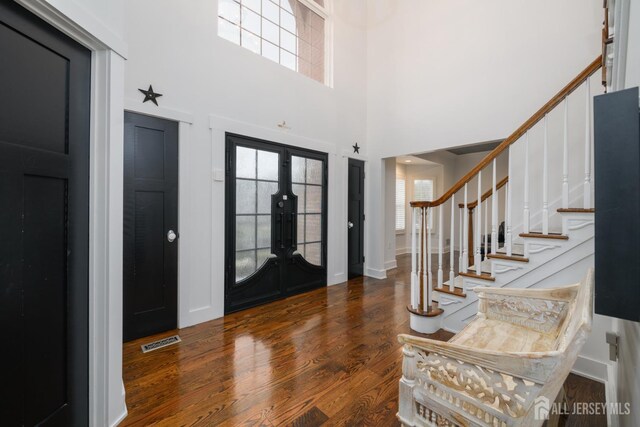 entrance foyer with a high ceiling, dark hardwood / wood-style flooring, and french doors