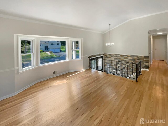 unfurnished living room with a chandelier, crown molding, plenty of natural light, and light hardwood / wood-style floors