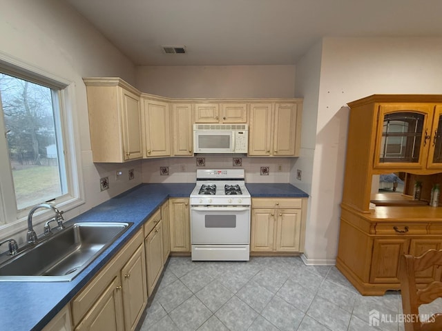 kitchen with light tile patterned flooring, white appliances, sink, and backsplash