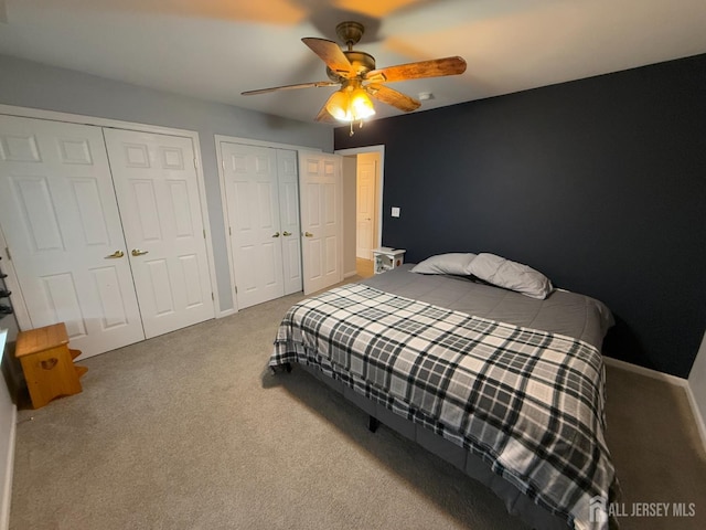 bedroom with ceiling fan, multiple closets, and carpet flooring