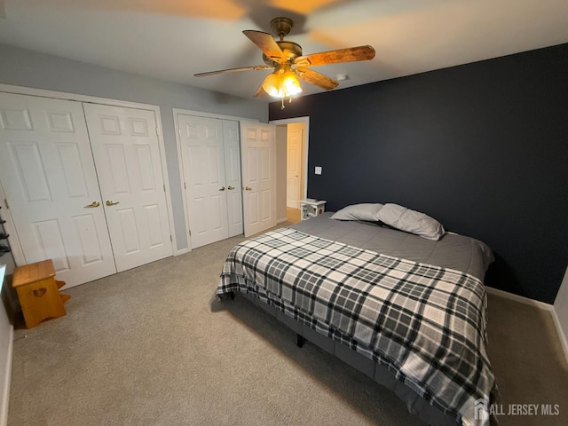 carpeted bedroom featuring multiple closets, a ceiling fan, and baseboards