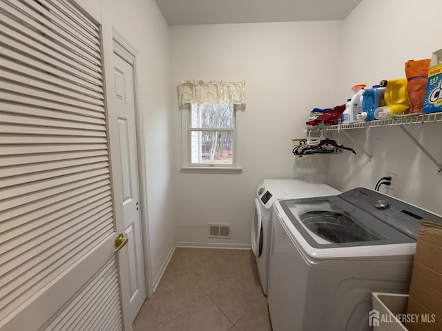 clothes washing area with light tile patterned floors and washer and clothes dryer