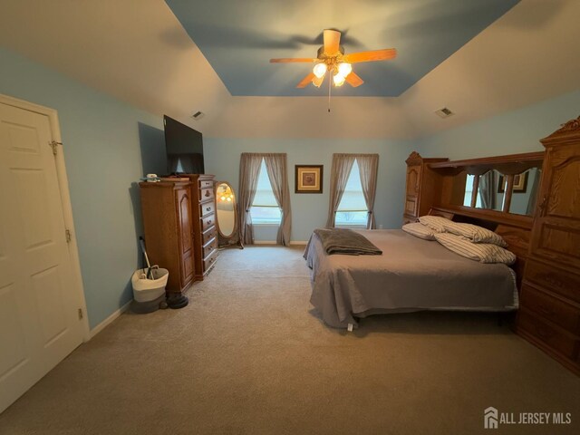 bedroom with light carpet, a raised ceiling, and ceiling fan