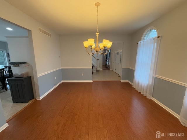 unfurnished dining area with hardwood / wood-style floors and a notable chandelier