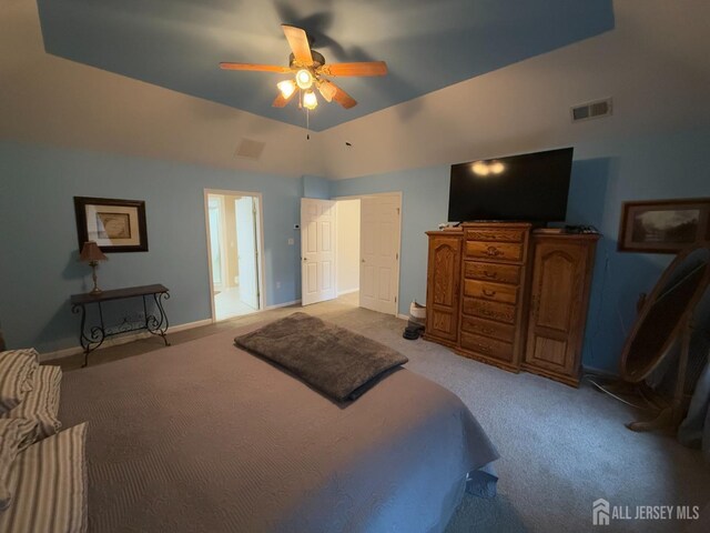 bedroom featuring a raised ceiling, light carpet, and ceiling fan