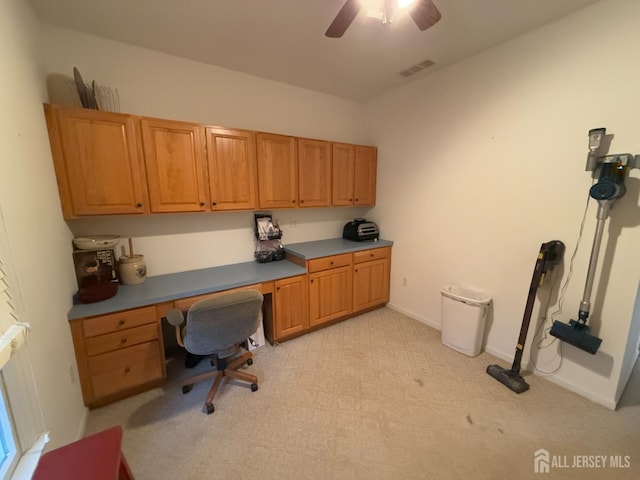 office area featuring built in desk, ceiling fan, and light carpet