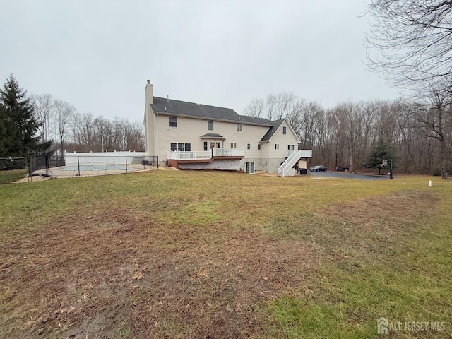 rear view of house with a pool side deck and a yard