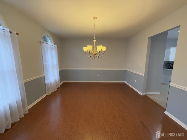 unfurnished dining area featuring a chandelier, wood finished floors, and baseboards