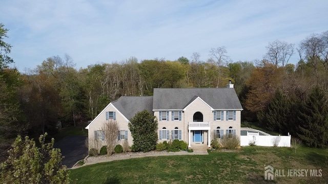 colonial inspired home featuring a wooded view and a chimney