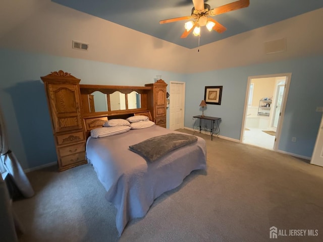 bedroom featuring light carpet, lofted ceiling, baseboards, ensuite bath, and ceiling fan