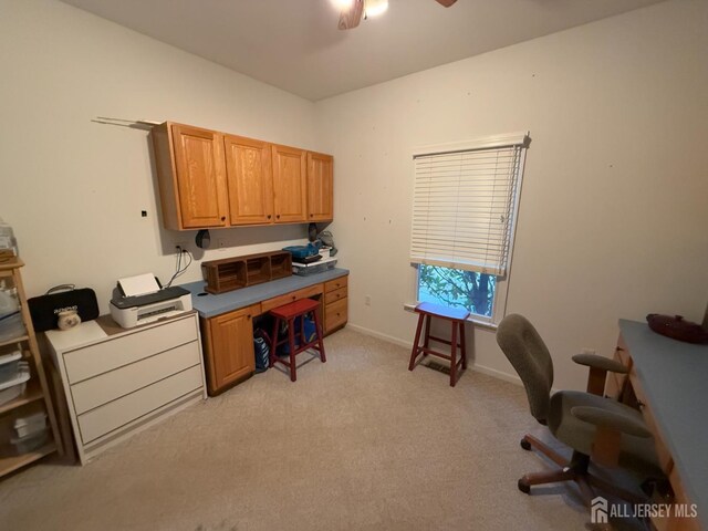 office area featuring light carpet, a ceiling fan, and baseboards