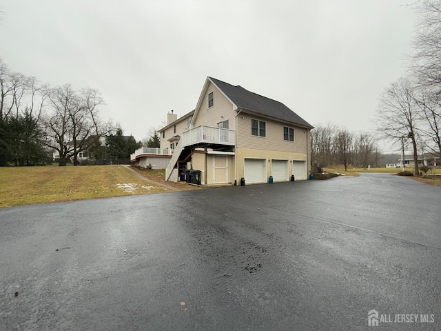 view of side of property featuring a yard, a garage, and a wooden deck