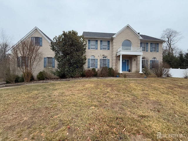 view of front of property featuring a front yard, a balcony, and fence