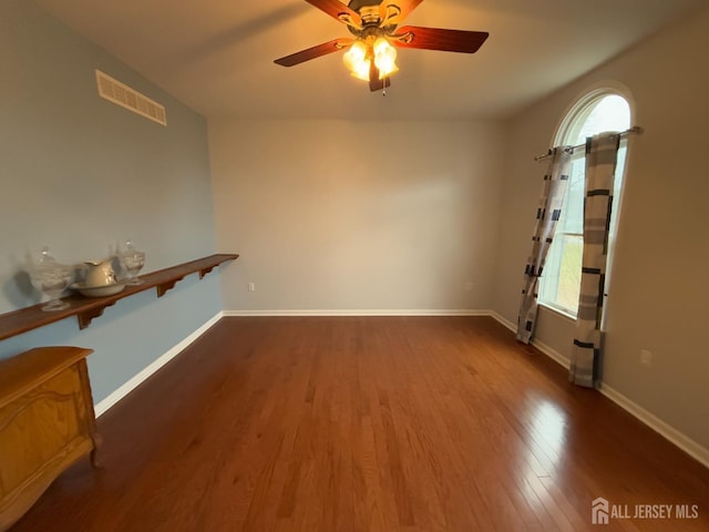 spare room with a ceiling fan, wood finished floors, and baseboards