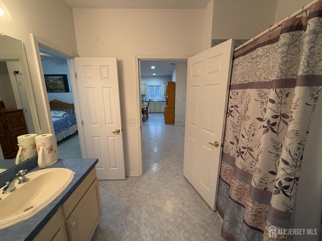 ensuite bathroom featuring tile patterned flooring, vanity, and a shower with shower curtain