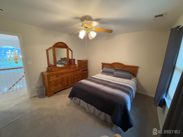 carpeted bedroom with ceiling fan with notable chandelier