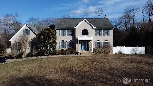 view of front of home featuring a front lawn, a balcony, and fence