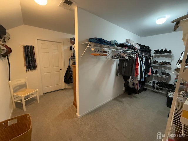 walk in closet with vaulted ceiling and carpet floors