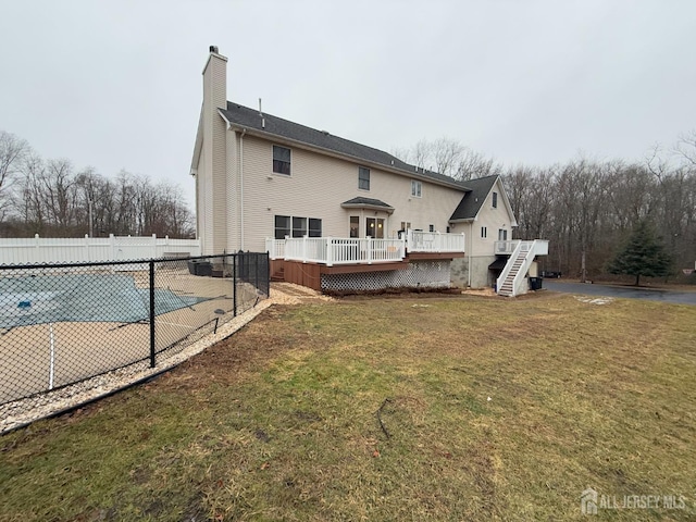 rear view of house with a pool side deck and a lawn