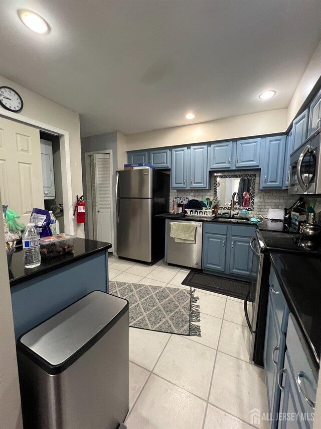354 Burdock Ct, Readington, NJ 08887 - kitchen with stainless steel appliances, a sink, blue cabinets, dark countertops, and light tile patterned floors