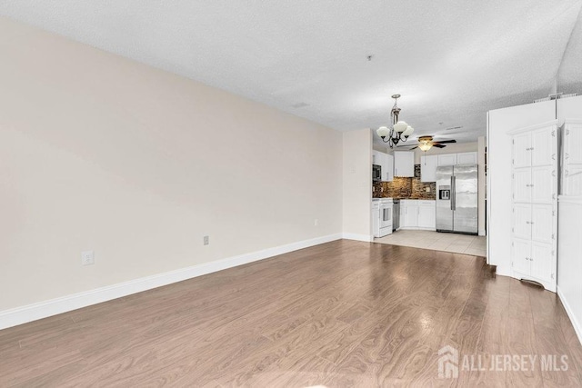 46 Prestwick Way, Edison, NJ 08820 - unfurnished living room with a chandelier, light wood-type flooring, baseboards, and a textured ceiling