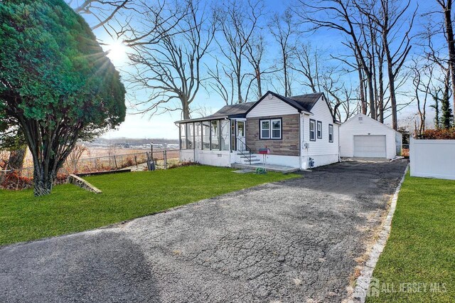 view of front of property with a sunroom, a garage, an outdoor structure, and a front yard