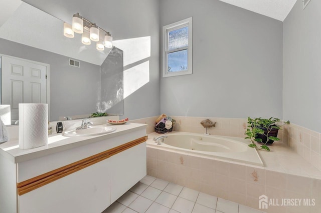 bathroom with tiled tub, tile patterned flooring, vanity, and a textured ceiling