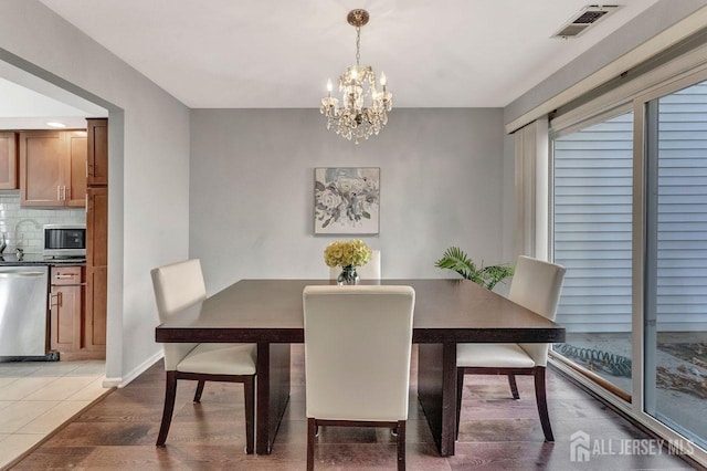 dining space with hardwood / wood-style floors and a notable chandelier