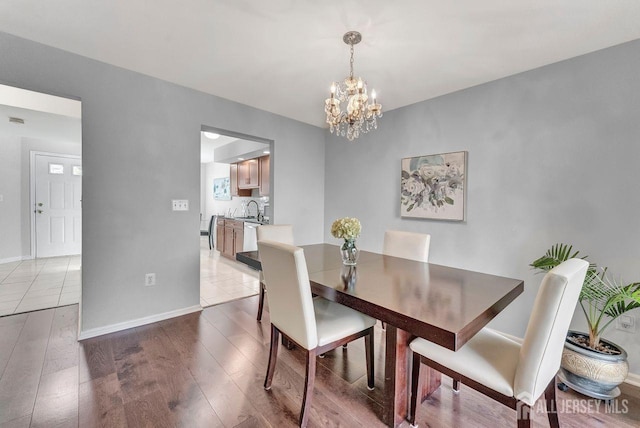 dining space featuring sink, an inviting chandelier, and light wood-type flooring