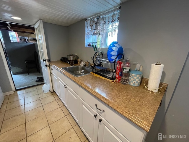 kitchen with light tile patterned floors, white cabinetry, and a sink
