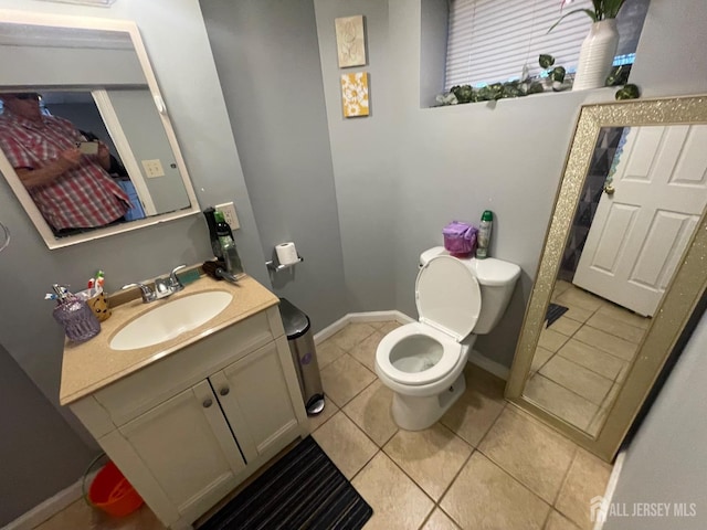 half bathroom with toilet, tile patterned flooring, vanity, and baseboards