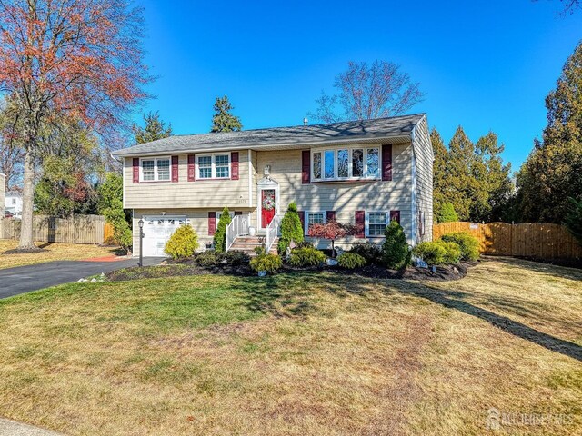 raised ranch with a front lawn and a garage