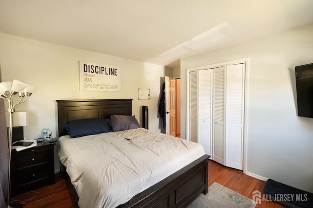 bedroom with baseboards, a closet, and dark wood-style floors