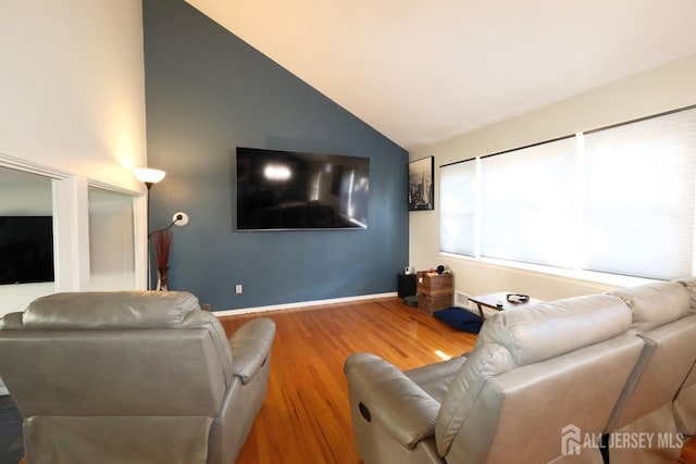 living area with wood finished floors, baseboards, and high vaulted ceiling