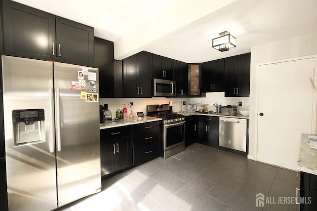 kitchen featuring dark cabinetry, tasteful backsplash, and appliances with stainless steel finishes