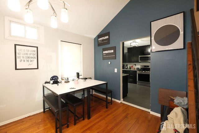 dining room with baseboards, wood finished floors, and lofted ceiling