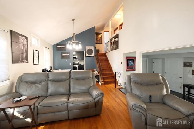 living room with stairway, high vaulted ceiling, and wood finished floors
