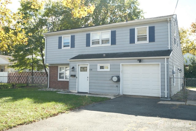 view of front facade with a garage, fence, aphalt driveway, a front lawn, and brick siding